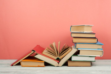 Book stacking. Open book, hardback books on wooden table and pink background. Back to school. Copy...