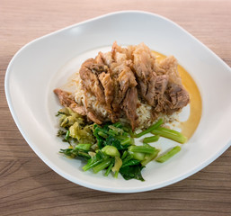 Traditional Thai style of braised pork belly on white rice served with chopped fermented cabbage and steamed kale