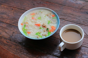 Thai rice soup with pork breakfast food and coffee on wooden background 