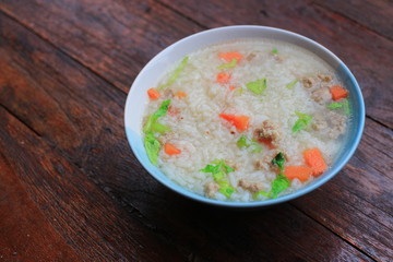 Thai rice soup with pork breakfast food on wooden background 