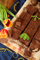 Brownie square pieces covered with cacao powder surrounded by red tulips