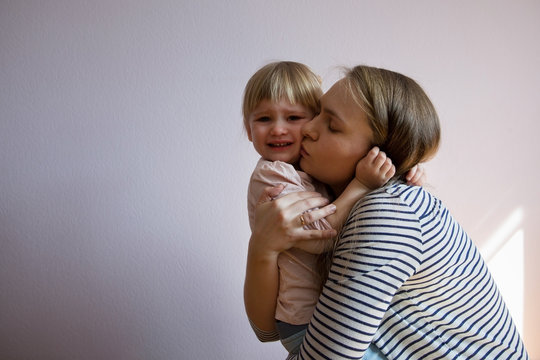 Weeping little girl is hugged by her mom. The rebellion of a two-year-old.