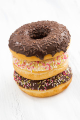 Glazed donuts on white wooden table, vertical