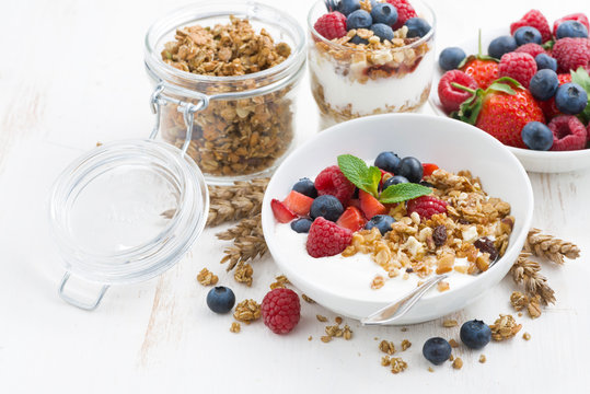 healthy breakfast with natural yogurt, muesli and berries on white wooden background, closeup