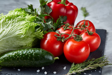 Bunch of fresh tomatoes with green leaves on stony board over white background, top view, close-up, selective focus