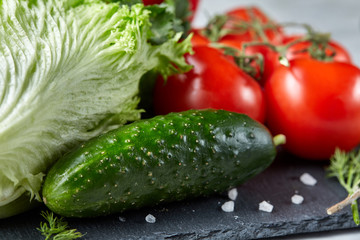 Bunch of fresh tomatoes with green leaves on stony board over white background, top view, close-up, selective focus
