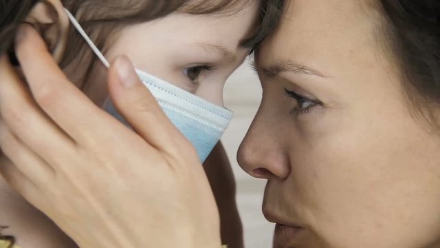 Sick child. Child in a medical mask. Mom hugs a sick child.