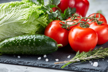 Bunch of fresh tomatoes with green leaves on stony board over white background, top view, close-up, selective focus