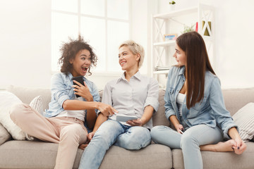 Three female friends using smartphones at home