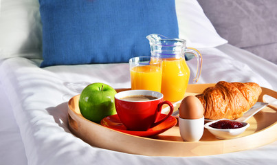 Breakfast on tray in bed in hotel room