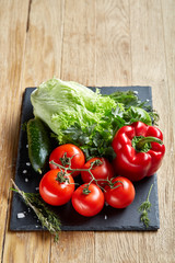 Close-up still life of assorted fresh vegetables and herbs on wooden rustic background, top view, selective focus.