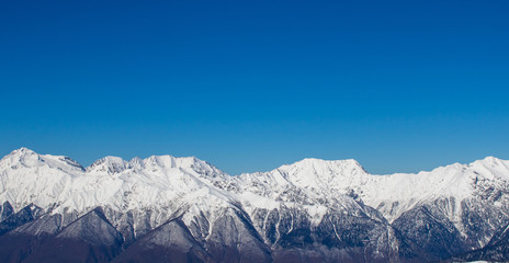 snow-covered mountains and forest against the blue sky
