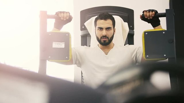 Handsome bearded man doing biceps workout in the gym