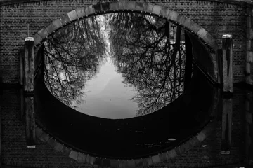 Foto op Plexiglas Kanaal water canals in Amsterdam with a bridge in the middle and traditional architecture black and white