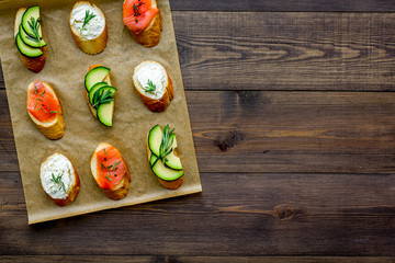 Healthy lunch with mini sandwiches cheese, fish and avocado on wooden background top view space for text