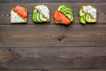 Healthy lunch with mini sandwiches cheese, fish and avocado on wooden background top view space for text