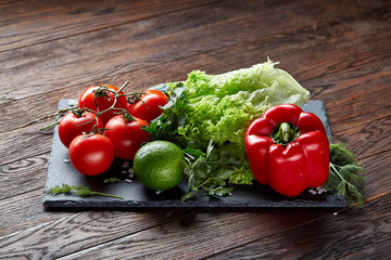 Close-up still life of assorted fresh vegetables and herbs on wooden rustic background, top view, selective focus.