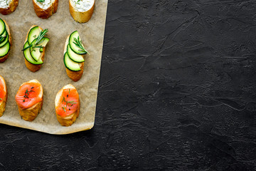 Mini sandwich set with french baguette, cheese, fish and avocado on black background top view mock up
