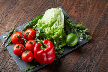 Close-up still life of assorted fresh vegetables and herbs on wooden rustic background, top view, selective focus.