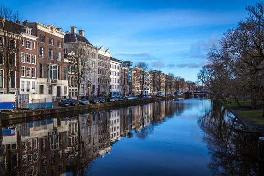 water canals in Amsterdam with traditional architecture reflecting in water on a  sunny day with blue sky