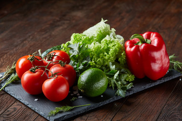 Close-up still life of assorted fresh vegetables and herbs on wooden rustic background, top view, selective focus.