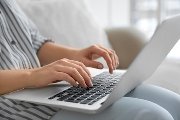 Young woman using laptop indoors, closeup