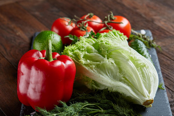 Close-up still life of assorted fresh vegetables and herbs on wooden rustic background, top view, selective focus.