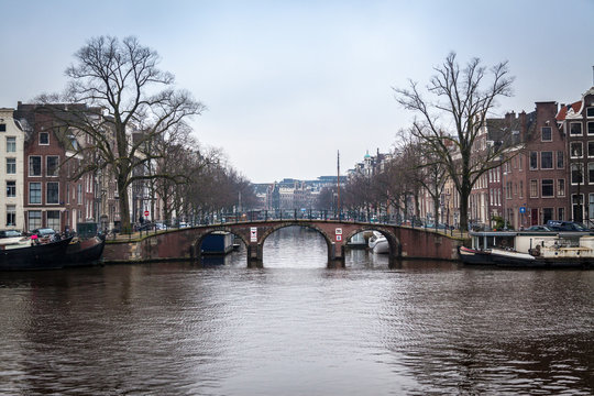 water canals in Amsterdam with a bridge in the middle and buildings on both of bridge's side 