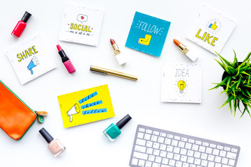Female blogger concept. Work desk with keyboard, cosmetics and social media icons on white desk top view