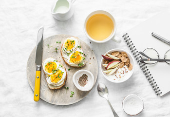 Morning breakfast table inspiration - sandwiches with cream cheese and boiled egg, yogurt with...