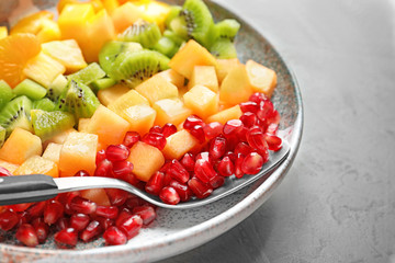 Plate with fresh cut fruits on table, closeup