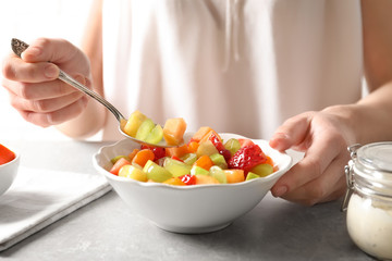 Woman with bowl of fresh fruit salad, closeup