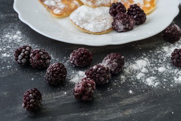 Homemade pancakes with blackberries, powdered sugar. Dark background.