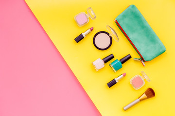 Beauty set with decorative cosmetics. Nail polish, brushes and bag on yellow and pink background top view mock-up