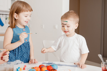 Mom and children paint eggs with colors. Have fun. Preparation for Easter.