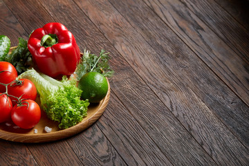 Close-up still life of assorted fresh vegetables and herbs on vintage wooden background, top view, selective focus.