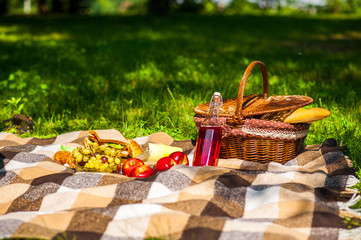 Picnic in nature. In the park or garden. Grapes apples sandwiches with wine or juice. Basket with...
