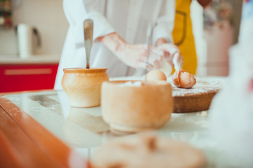 Male and female hands chef close-up, knead the dough, cook the dough on a kitchen.