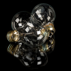 Three old incandescent light bulbs that are clear on black