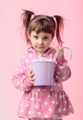 Cute little girl holding small violet bucket of marshmallow.