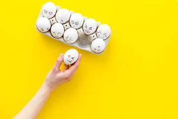Fototapeta na wymiar Basic emotions concept. Faces drawn on eggs. Happy, smile, sad, angry, in love. Yellow background top view copy space