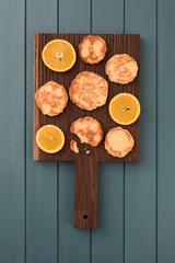Fototapeta na wymiar Healthy vegetarian snack. Homemade cookies and orange slices on oak cutting board on dark blue background copyspace