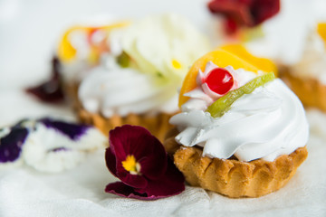 cake with fresh fruit and edible flowers Pansy Flowers on light background