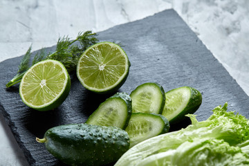Concept of fresh green lettuce, cucumber, dill, lime on a light background, selective focus, top view, copy space.
