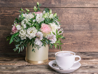 Wedding bouquet in a box and coffee latte in a white cup on a wooden background