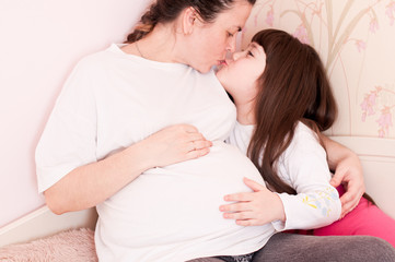 Close-up of a pregnant woman with a child touching her belly, the concept of expecting a child and family
