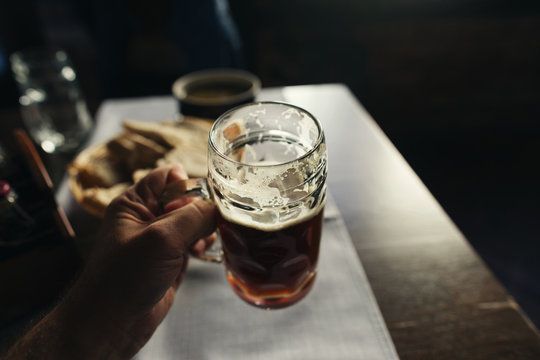 Glass Of Fresh Dark Beer In Male Hand Close Up