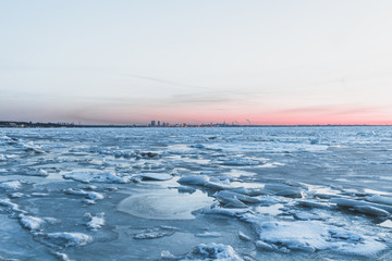 Icey Baltic sea with Tallinn's skyline behind it during a sunset