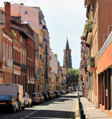 Fototapeta na wymiar View of Saint Sernin basilica from a typical colorful street of Toulouse, Haute Garonne, Occitanie region, France