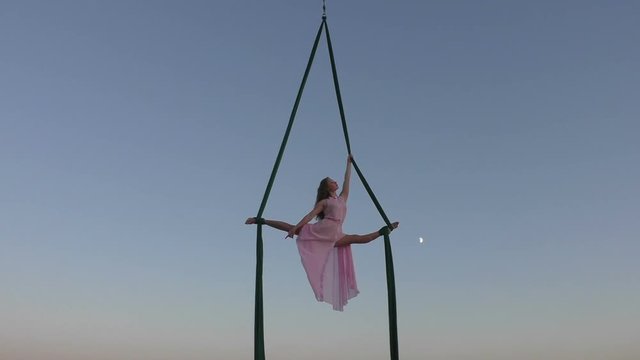 Woman aerial acrobat in the sky, she shows the show at altitude.